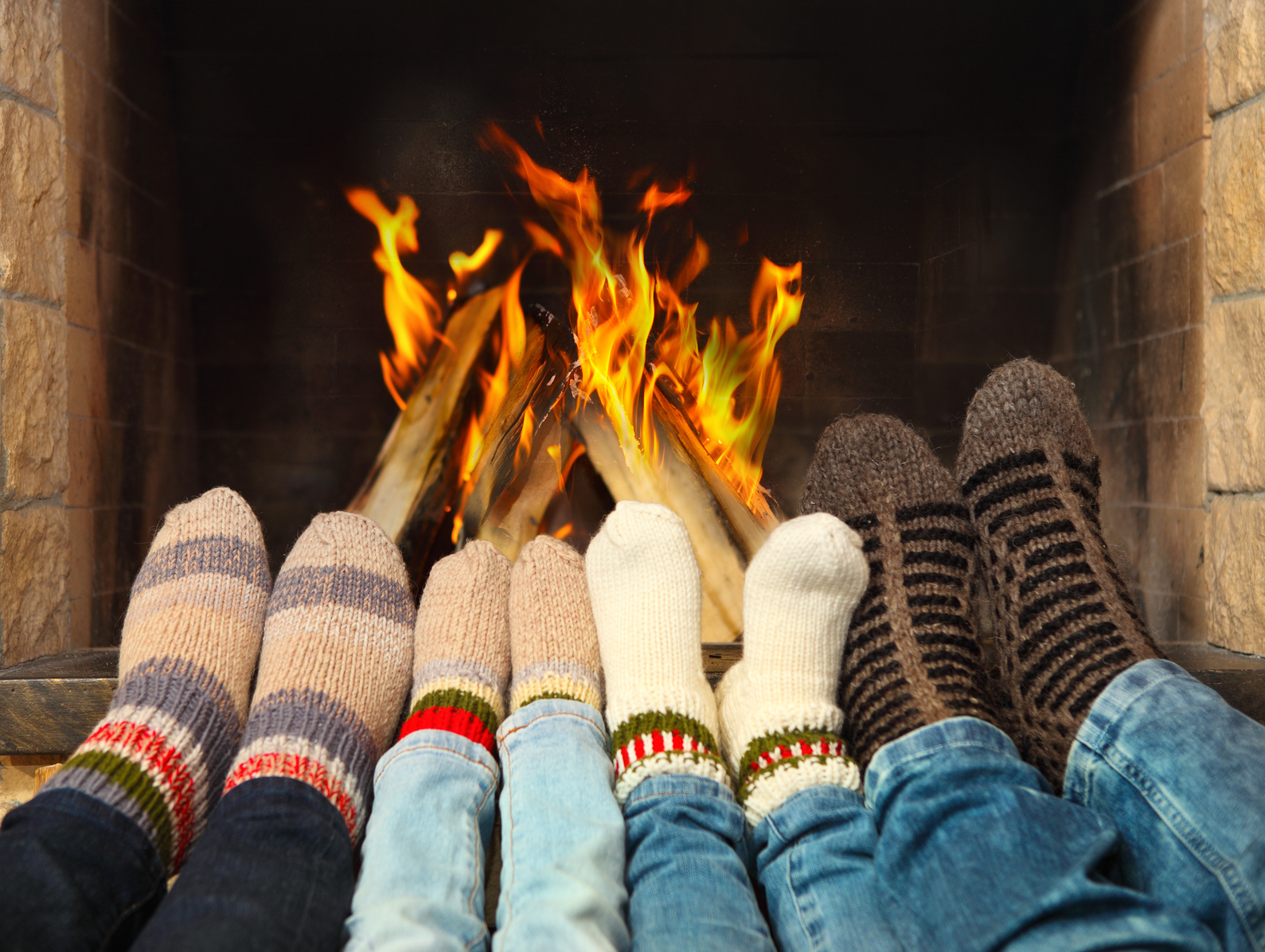 Feets of a family wearing woolen socks warming near the fireplace