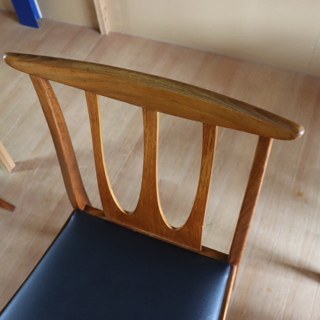 Vintage G-Plan teak dining chair with curved slat back and black leather seat, British mid-century design.