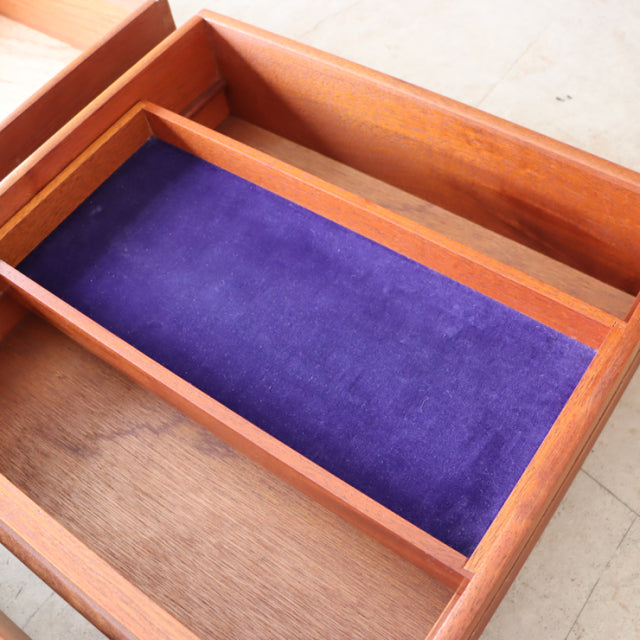 Open drawer of vintage G-Plan mid-century teak desk showing rich wood grain and purple velvet lining.