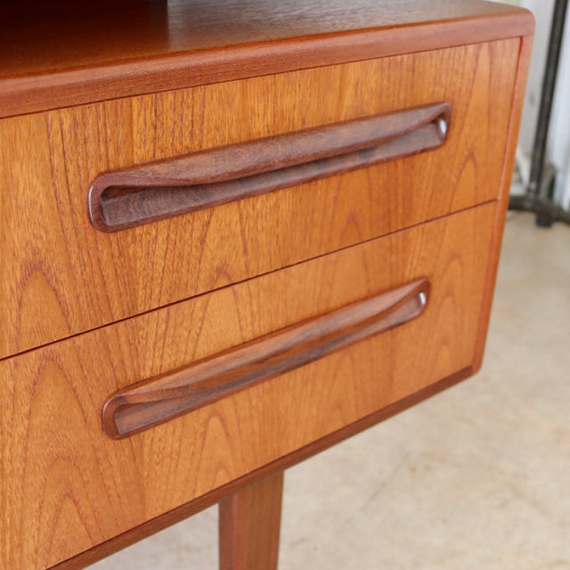 Vintage British G-Plan mid-century teak desk drawer front with smooth wood grain and sculpted dark teak handles.