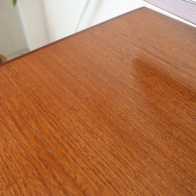 Close-up of vintage British mid-century G-Plan teak desk surface showing warm wood grain and smooth finish.