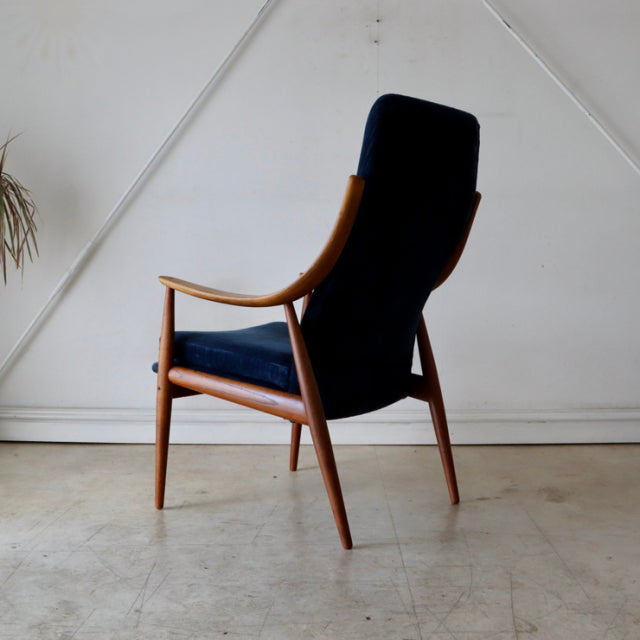 Mid-century vintage Danish highback chair in teak with dark blue upholstery and slender angled legs.