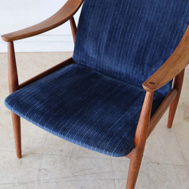 Mid-century Danish teak armchair with curved armrests and deep blue corduroy upholstery, vintage British style.