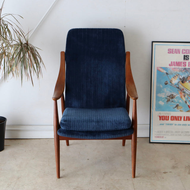 Mid-century vintage Danish armchair with teak frame and navy blue corduroy upholstery, slender angled legs, and gently.