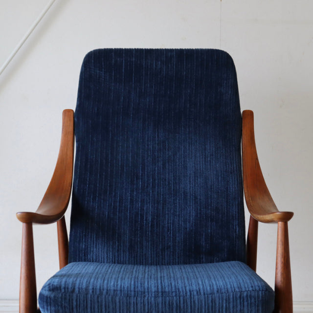 Mid-century Danish teak armchair with vintage deep blue corduroy upholstery and elegant curved wooden arms.