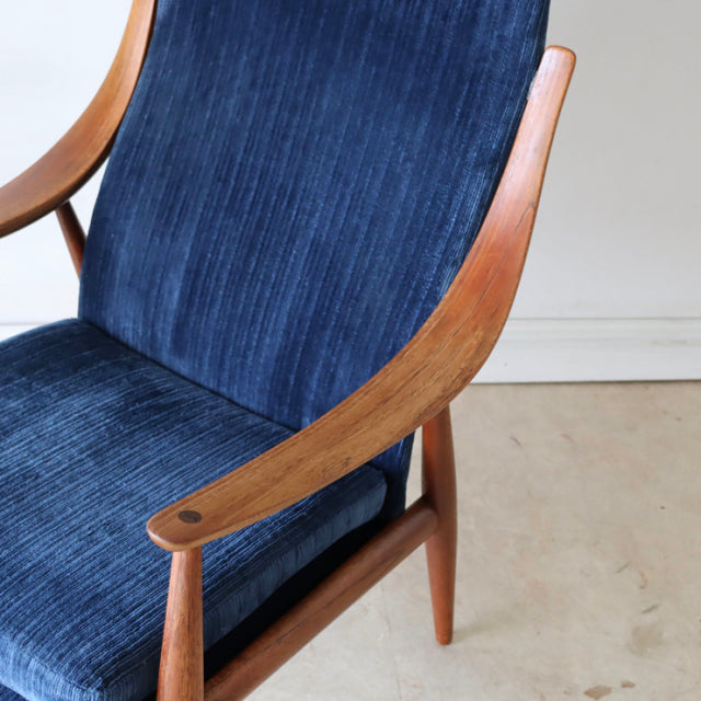 Mid-century vintage Danish teak armchair with deep blue ribbed upholstery and sculpted wooden frame.
