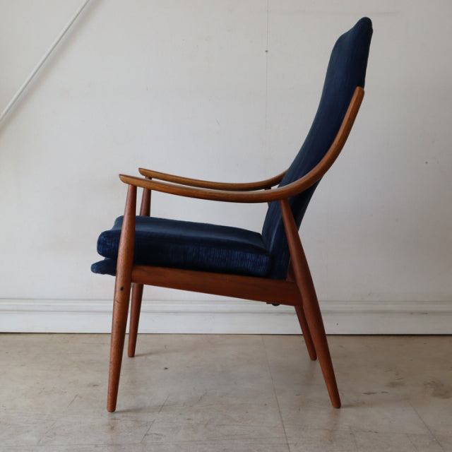 Mid-century Danish vintage teak armchair with navy highback upholstery and tapered legs.