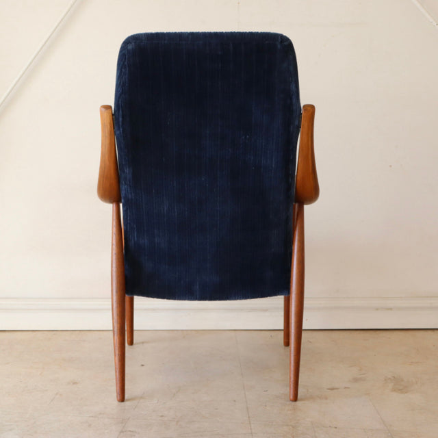 Mid-century vintage teak armchair with tall navy velvet back, sleek wooden legs, and Danish design.