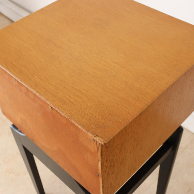 Vintage teak bedside cabinet showcasing warm wood grain and clean mid-century British design with sturdy black legs.