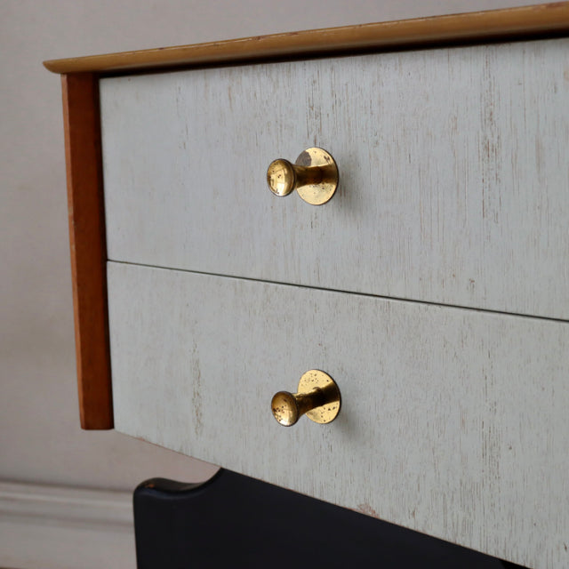 Mid-century British vintage teak bedside cabinet with light painted drawers and brass round knobs, smooth wood grain edge.
