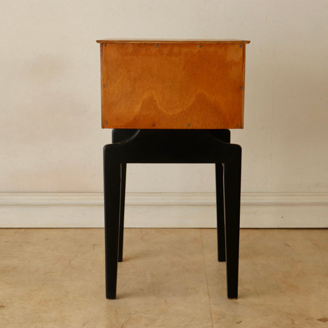 British mid-century teak bedside cabinet with rich wood grain, elevated on sleek black wooden legs from Denmark vintage.
