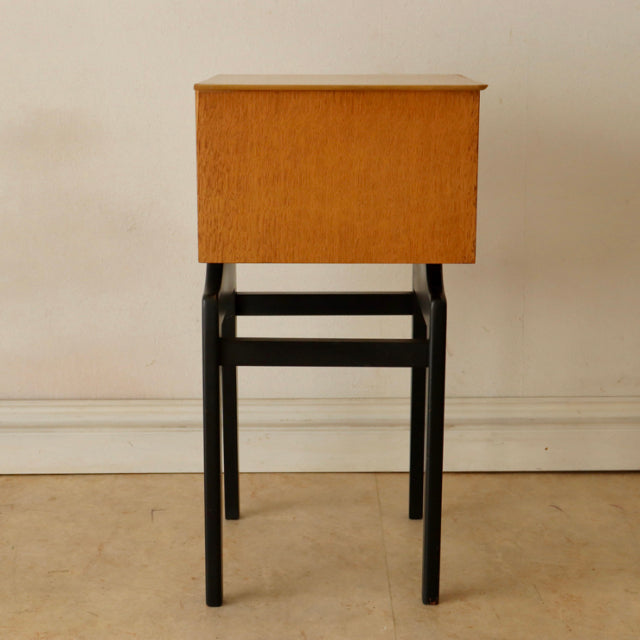 Mid-century British vintage teak bedside cabinet with black painted slender legs and rectangular form.