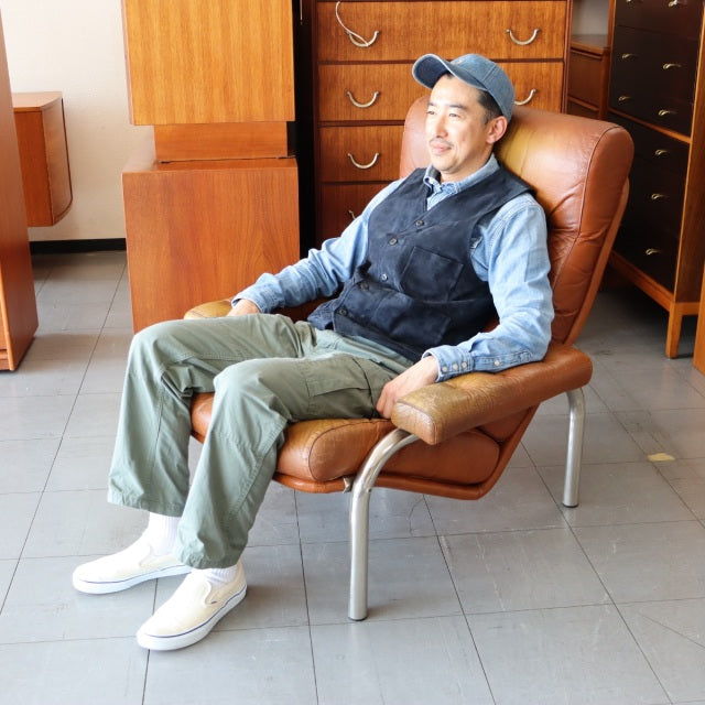 Mid-century vintage British leather sofa with smooth teak wood accents and sleek metal legs, showcasing rich patina and.