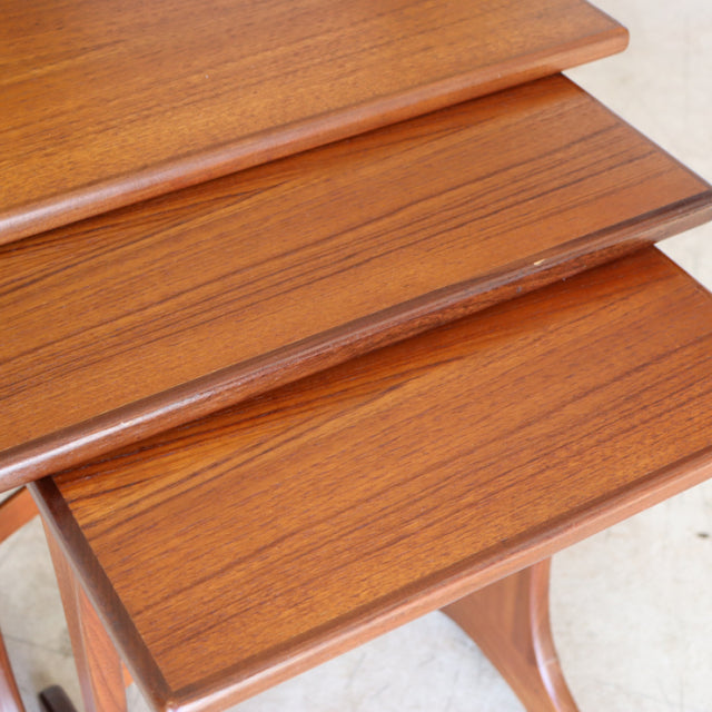 Set of three vintage British G-Plan teak nest tables with smooth wood grain and tapered legs, mid-century Denmark style.
