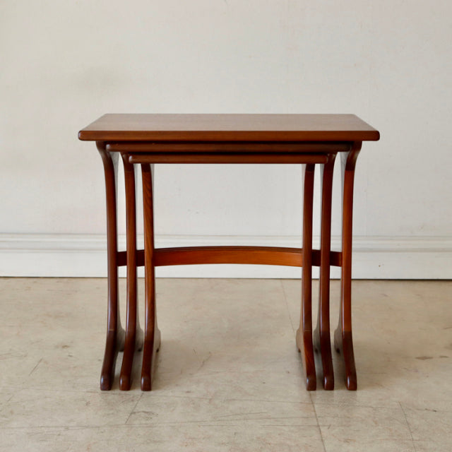 Set of three vintage British G-Plan teak nesting tables with smooth wood grain and slender arched legs, mid-century Danish.