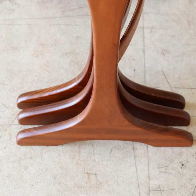 Set of three vintage teak G-Plan British mid-century nest tables with curved legs and smooth wood grain.