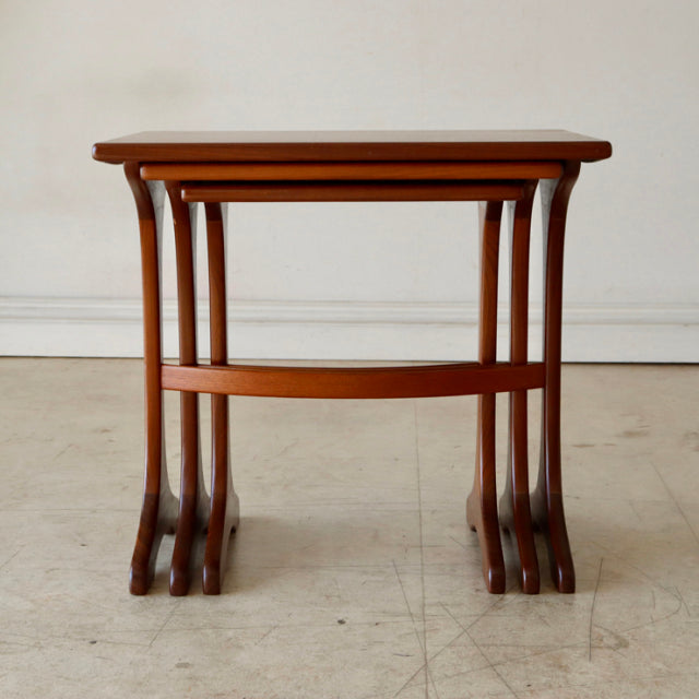 Set of three vintage British G-Plan teak nesting tables with curved legs and smooth wood grain, mid-century design.