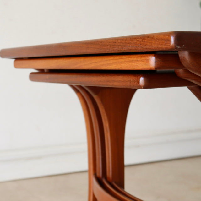 Vintage teak G-Plan nest tables with smooth wood grain and sculpted mid-century British curved legs.