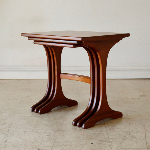 Vintage British G-Plan teak nest tables with mid-century curved legs and smooth wood grain finish.