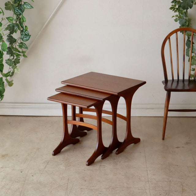 Set of three vintage British G-Plan teak nesting tables with mid-century curved legs and smooth wood grain finish.