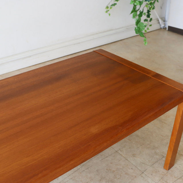 Vintage British mid-century teak coffee table with smooth wood grain, slender tapered legs, and a simple rectangular form.