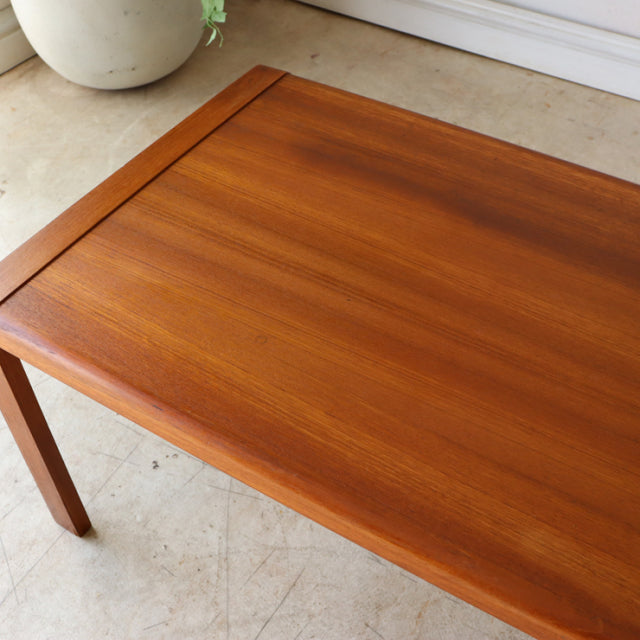 Mid-century British vintage teak coffee table with rich wood grain and clean rectangular top on slender legs.