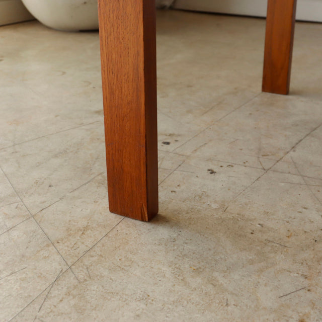 Mid-century British vintage teak coffee table leg with smooth wood grain and clean rectangular profile on concrete floor.
