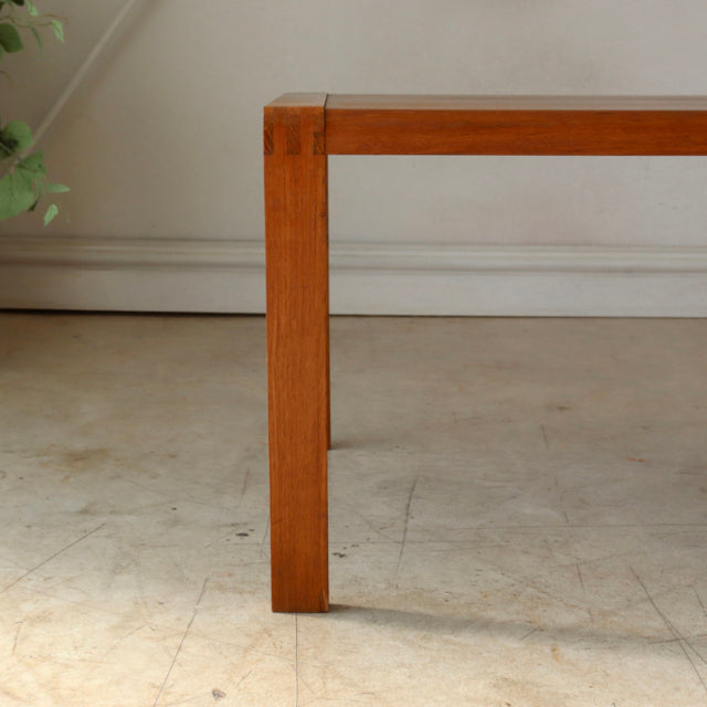Mid-century British vintage teak coffee table corner showing warm wood grain and clean, square legs with simple joinery.