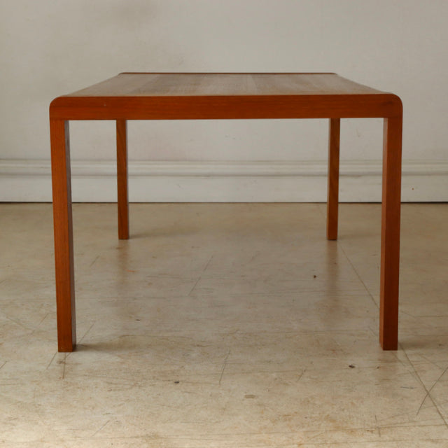 Mid-century British vintage teak coffee table with clean rectangular top and slender tapered legs, showcasing rich wood.
