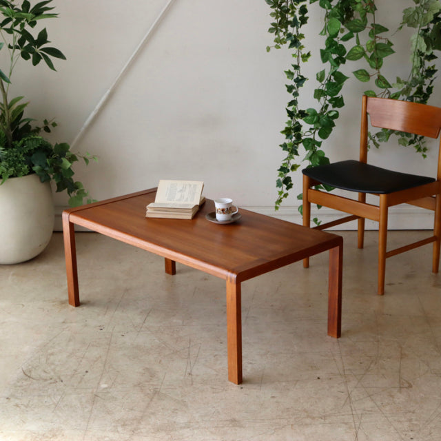 Mid-century British vintage teak coffee table with clean lines, visible wood grain, and slim tapered legs, paired with a.