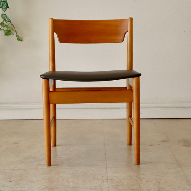 Mid-century British vintage teak dining chair with natural wood grain and black upholstered seat.