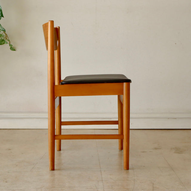 Mid-century British vintage teak dining chair with black upholstered seat and slender vertical slat back.