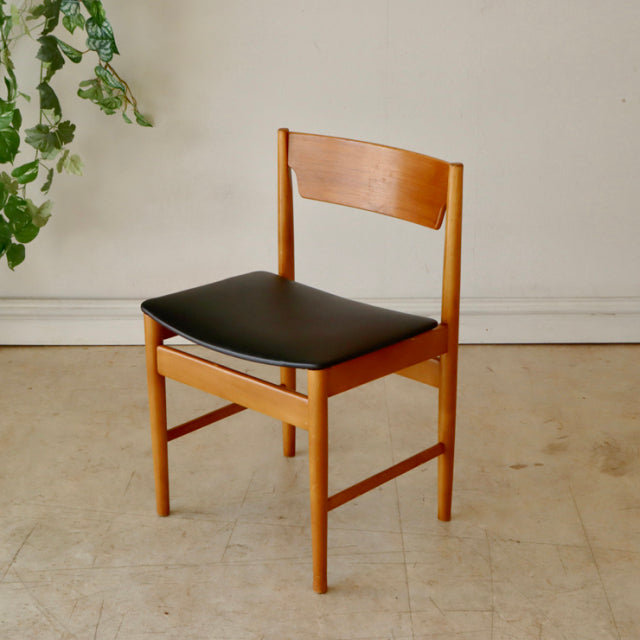 Mid-century British vintage teak dining chair with smooth curved backrest and black cushioned seat.