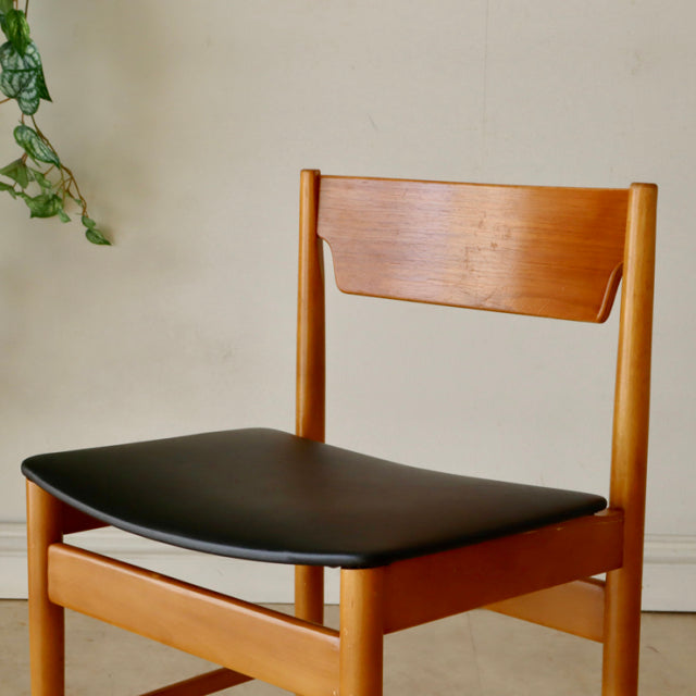 Mid-century British vintage teak dining chair with smooth wood grain and black upholstered seat.