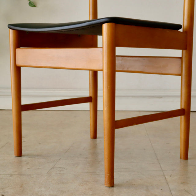 Mid-century British vintage teak dining chair with smooth wood grain and black upholstered seat, natural finish legs.