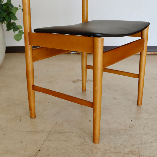 Vintage British mid-century teak dining chair with smooth wood grain and black cushioned seat, showcasing clean lines and.