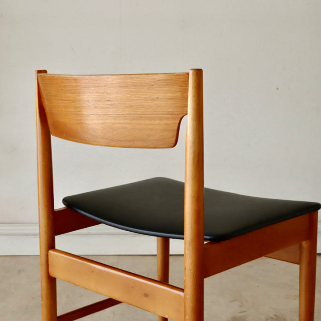 Mid-century British vintage teak dining chair with curved slat back and black upholstered seat.
