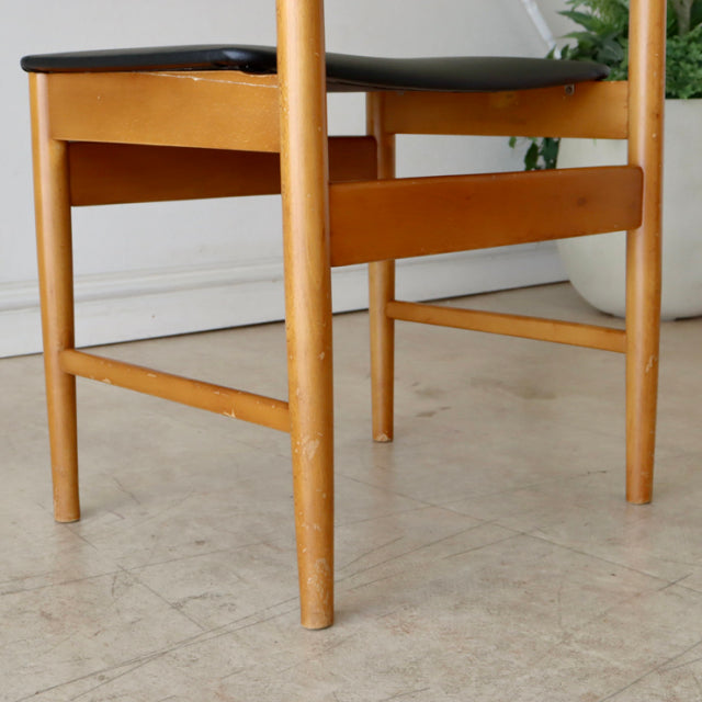 Mid-century British vintage dining chair with natural teak frame and black upholstered seat, smooth wood grain, slender.