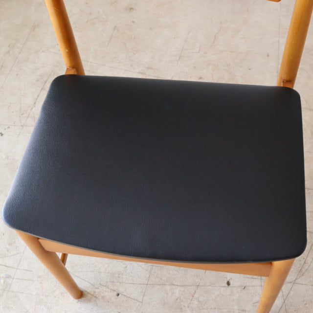 Mid-century British vintage teak dining chair with black cushioned seat and smooth wood grain legs.