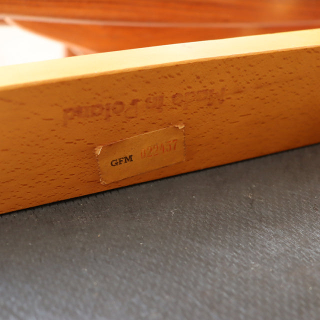 Close-up of a teak wood frame with vintage British mid-century dining chair stamp and product label on light wood grain.