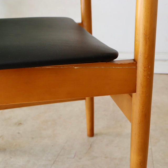 Mid-century British vintage teak dining chair with smooth wood grain and black upholstered seat.