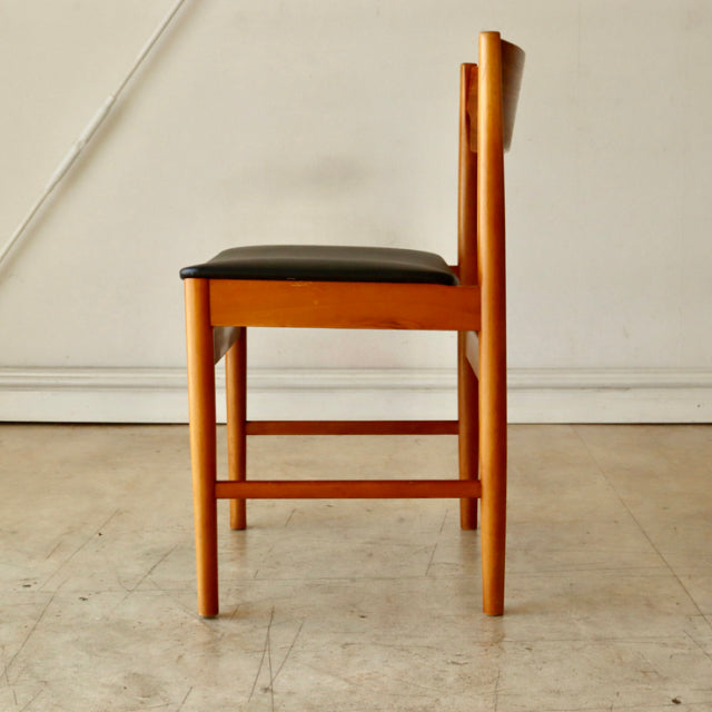 Mid-century British vintage teak dining chair with black upholstered seat and straight legs, side view.