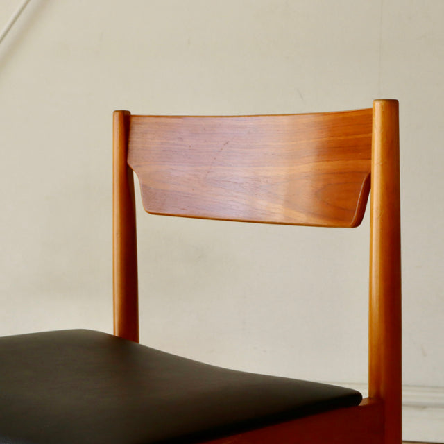 Mid-century British vintage teak dining chair with a smooth curved backrest and black upholstered seat.