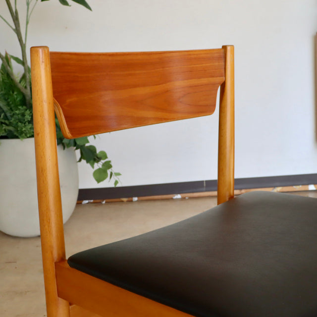Mid-century British vintage teak dining chair with smooth wood grain and black upholstered seat.