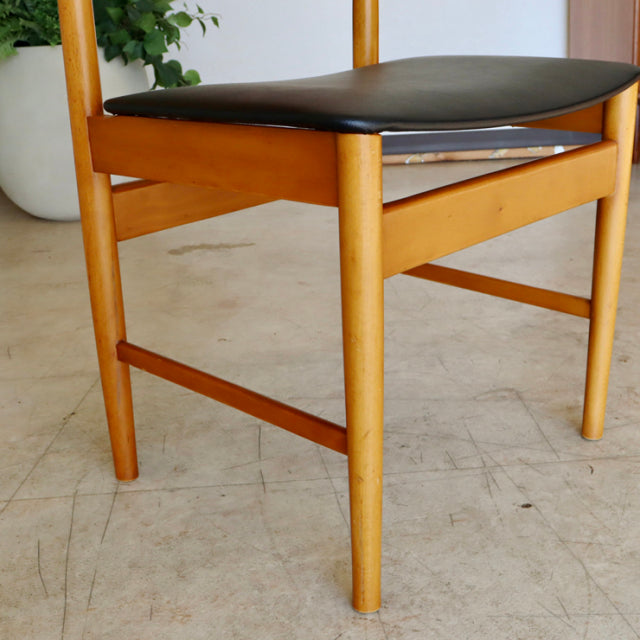 Mid-century British vintage teak dining chair with smooth wood grain and black upholstered seat.