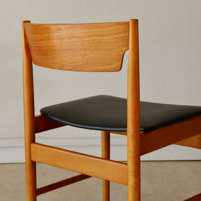 Vintage teak dining chair with black upholstered seat, British mid-century design from Denmark, smooth wood grain and.