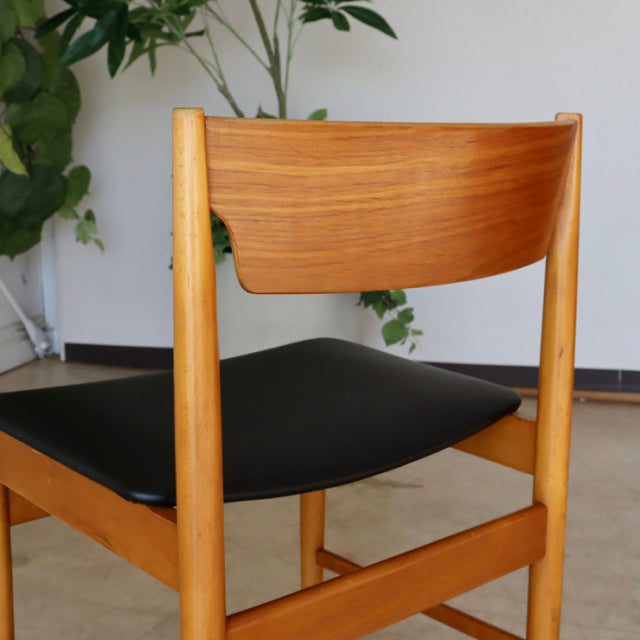 Vintage British mid-century teak dining chair with curved wooden backrest and black leather seat upholstery.