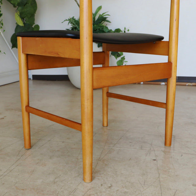 Mid-century teak dining chair with British vintage design, smooth wood grain and black cushioned seat from Denmark.