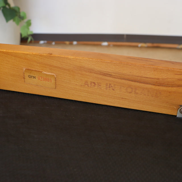 Close-up of vintage teak chair frame with British mid-century marking and natural wood grain detail.