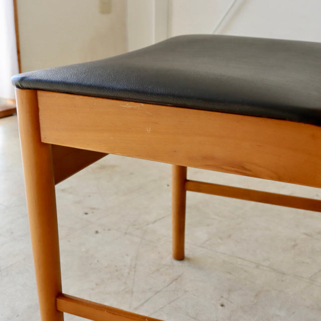 Mid-century British vintage dining chair in polished teak with smooth wood grain and black leather reupholstered seat.